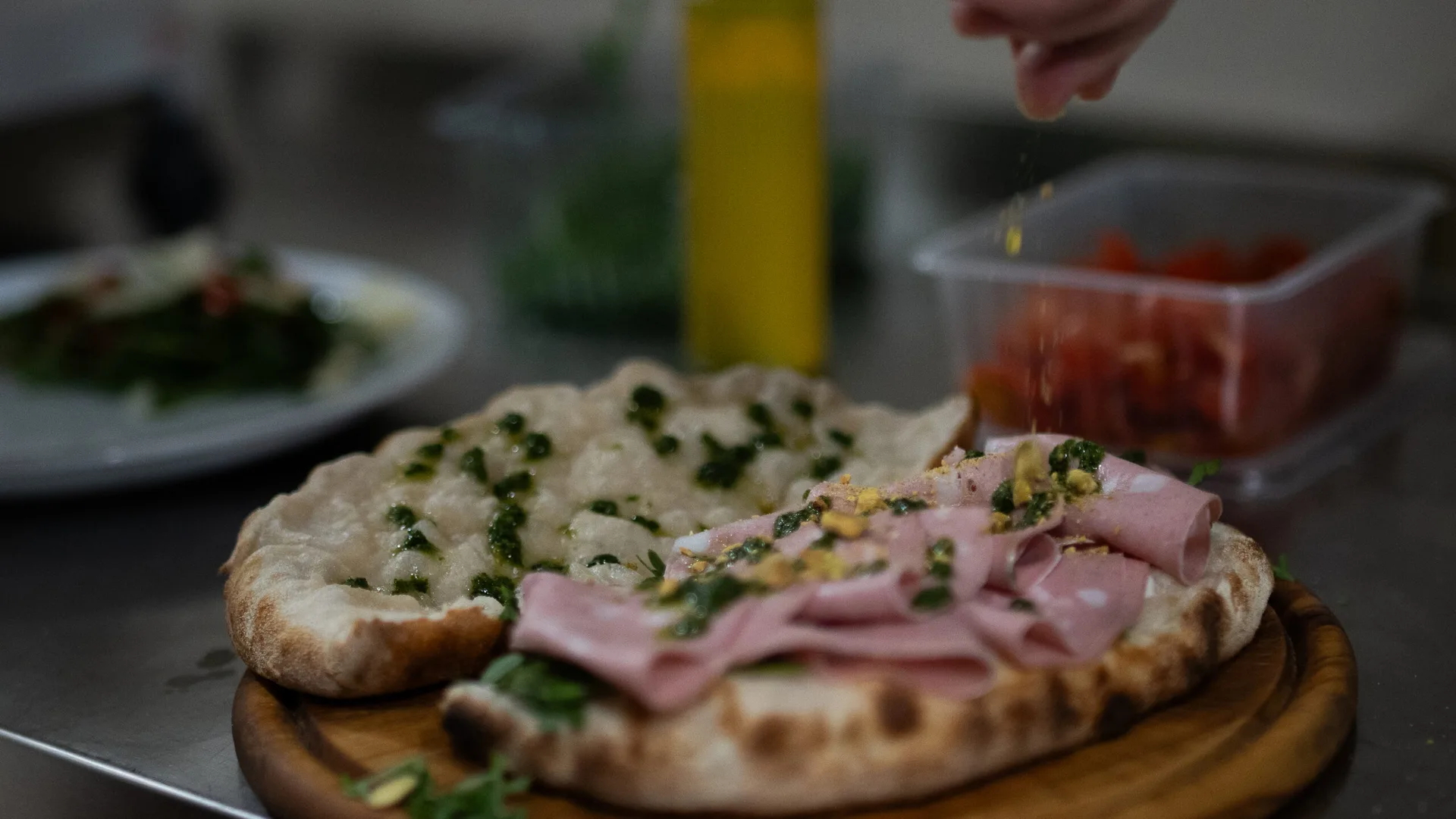 Pinsa so šunkou a pistáciovým crumble – Rímska pinsa s jemnou šunkou, bylinkami a pistáciovým crumble – dochucovaná čerstvým korením. Pizzeria Passage Košice