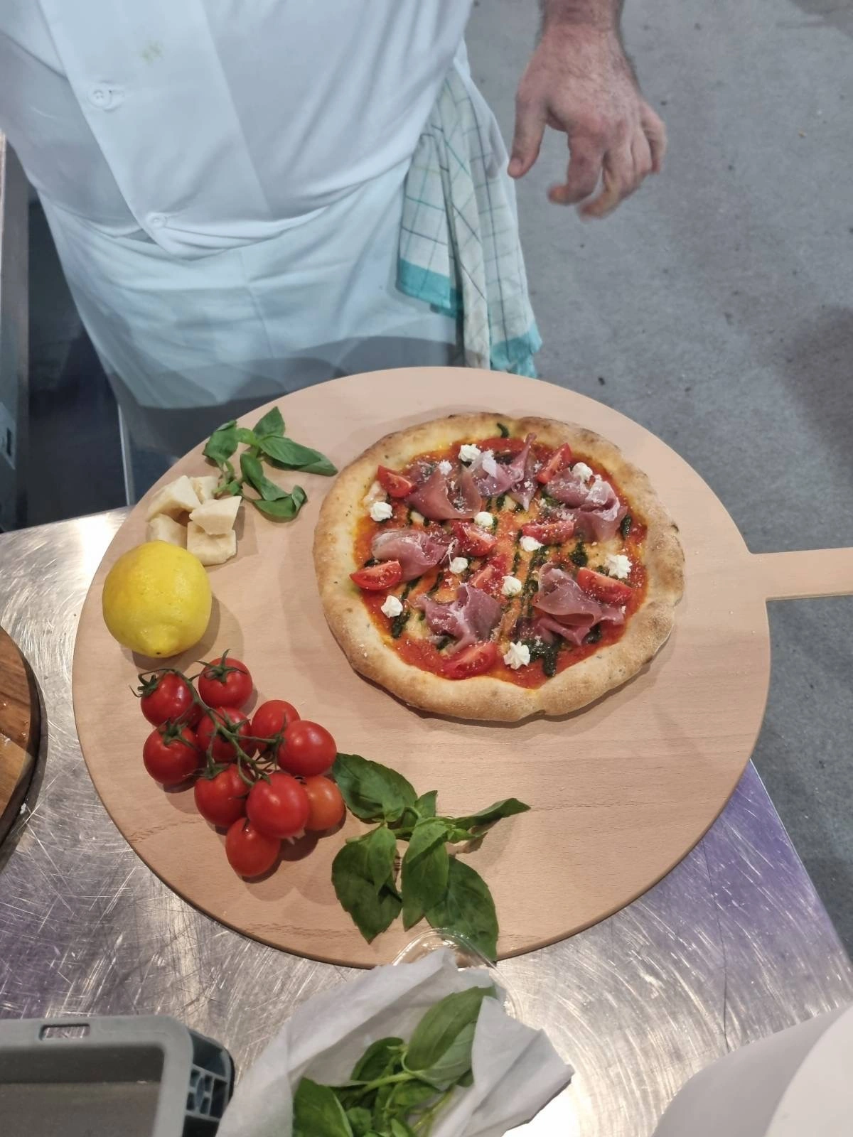 Hotová súťažná pizza s prosciuttom, čerstvými rajčinami a bazalkou
